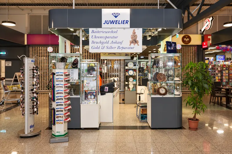 Außenansicht von Juwelier HADDAD: Verkaufsstand mit Schild „Juwelier“ und der Aufschrift Batteriewechsel, Uhrenreparatur, Bruchgold Ankauf, Gold und Silber Reparatur.
